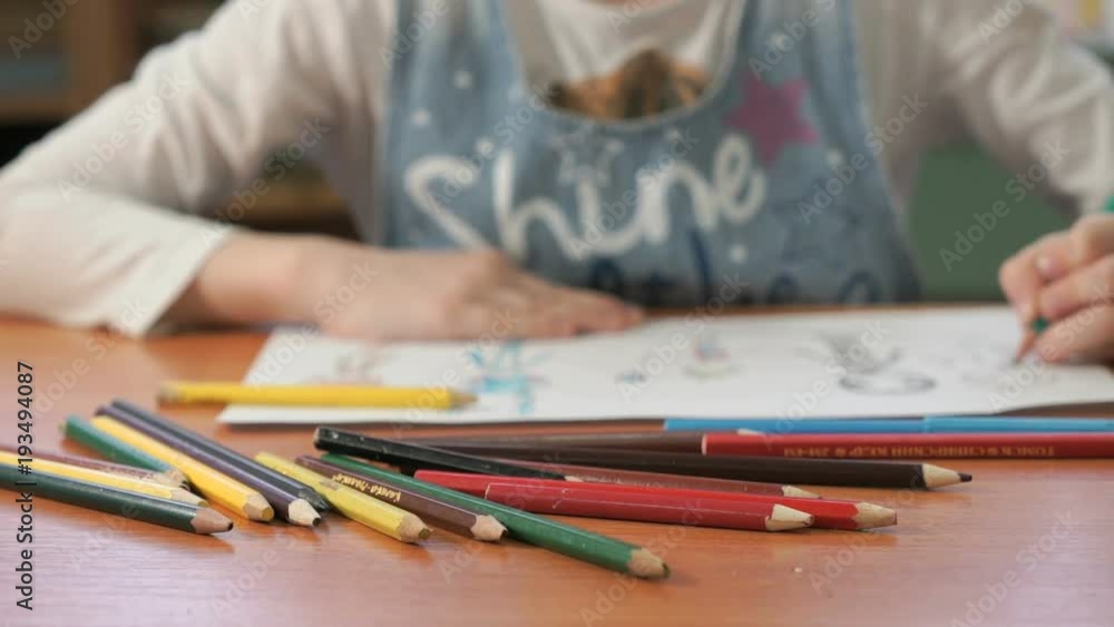 Close-up of unknown child draws the pictures using color pencils in the album in the kindergarten Close-up of unknown child draws the pictures using color pencils in the album in the kindergarten