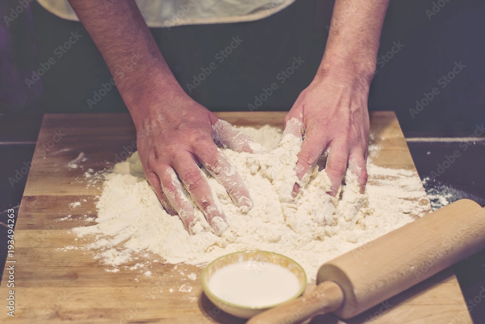 Hands rumple dough in kitchen