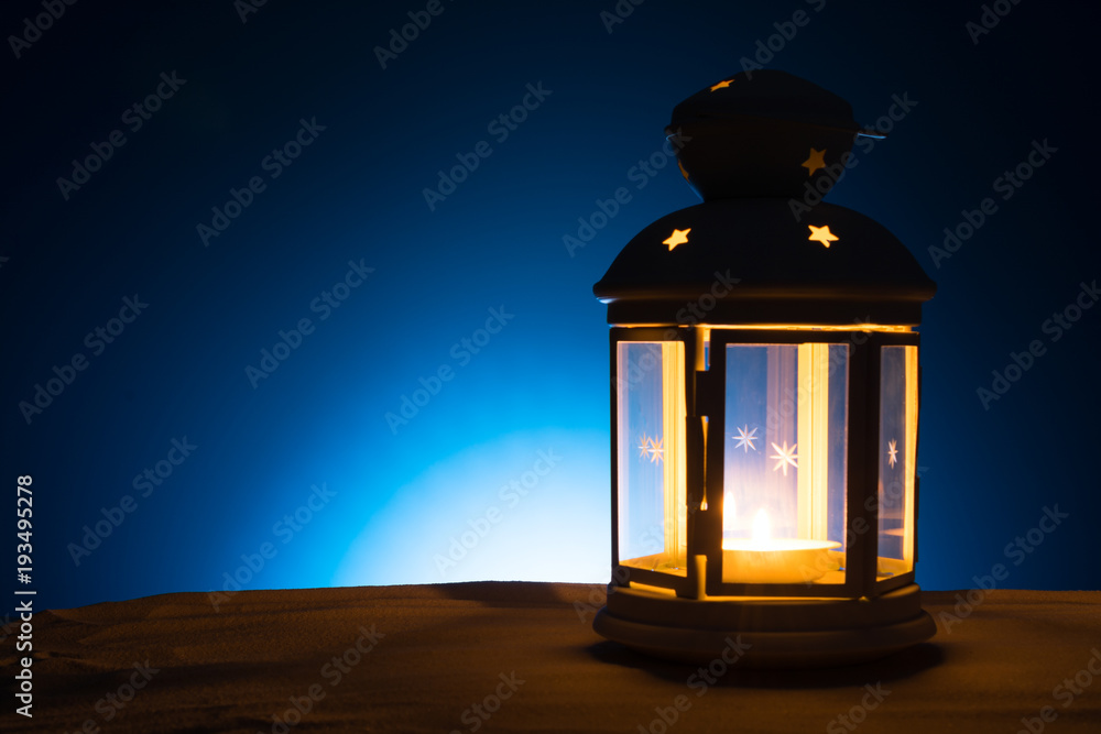 Holy month of Ramadan Karim background. Bright lantern on the sand with a copy space Holy month of Ramadan Karim background. Bright lantern on the sand with a copy space