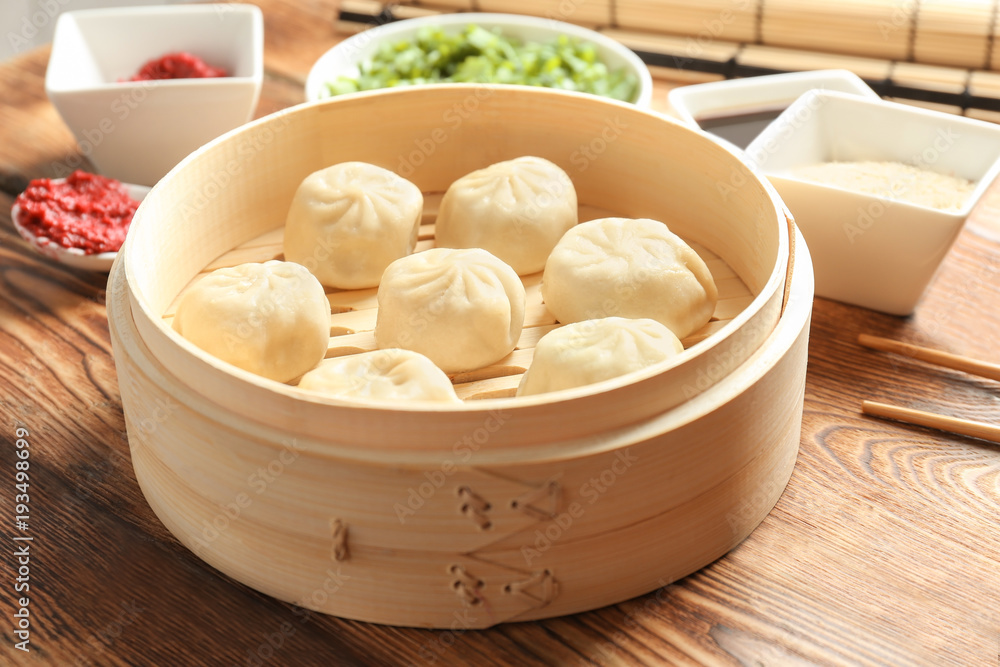 Bamboo steamer with tasty baozi dumplings on table