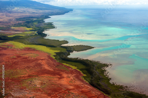 Aerial view of the colorful coast and Pacific water of the island of Molokai, Hawaii, shot from a small, low-flying prop plane
