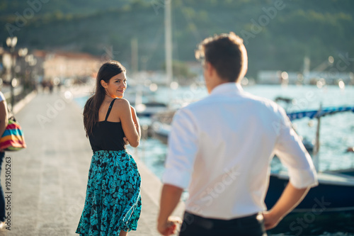 Shy flirty woman smiling to a man.Man giving a compliment to a introvert passing woman.Receiving a compliment on the street.Public complimenting.Flattering comment,feminine walking.Catcalling photo