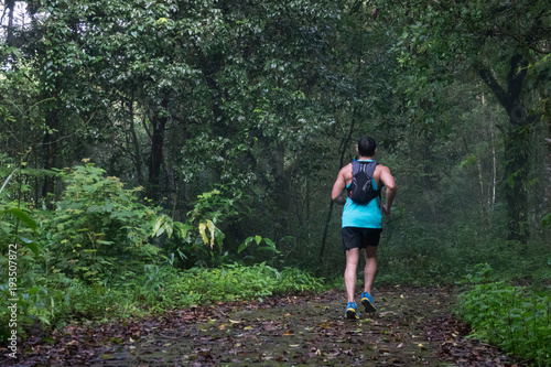 Athletic runner running on tropical forest trail, dramatic tone