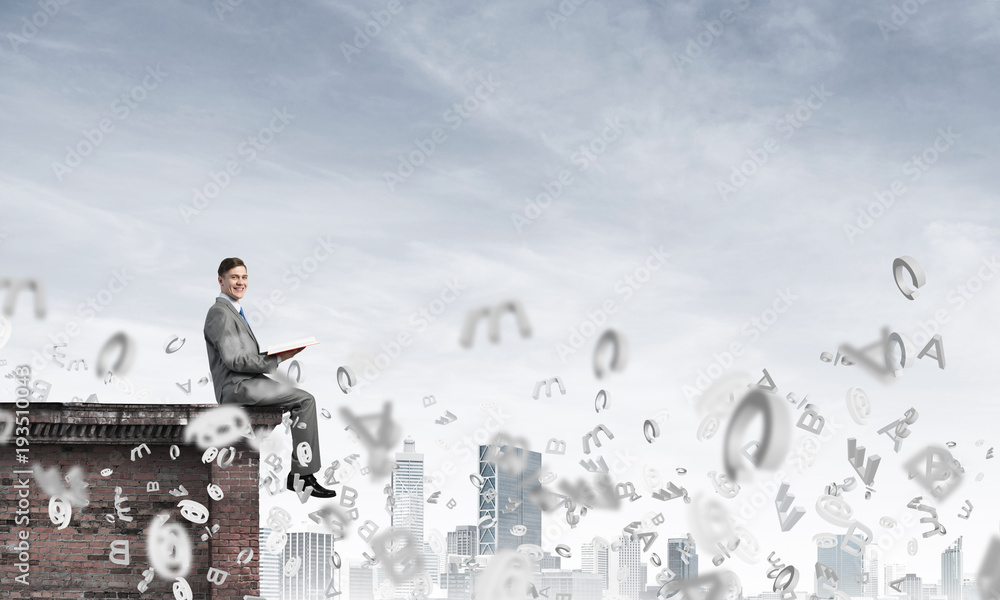 Man on roof edge reading book and symbols flying around Man on roof edge reading book and symbols flying around