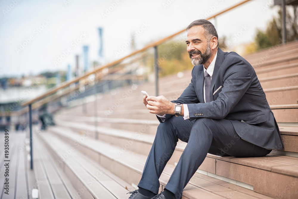 Senior businessman relaxing in an urban area, having a break from work Senior businessman relaxing in an urban area, having a break from work