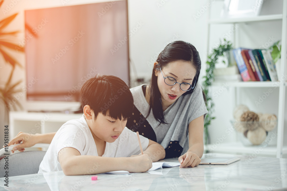 Asian boy with mother teaching and learning your homework at home Asian boy with mother teaching and learning your homework at home