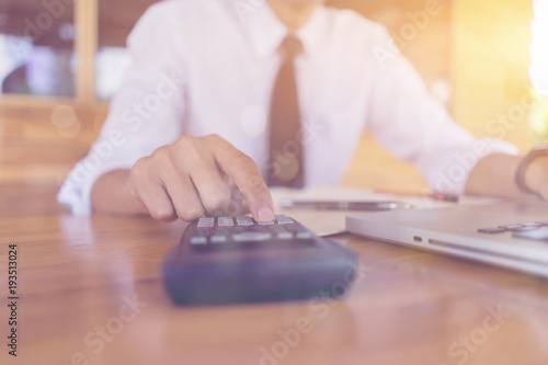 Businessman analyzing investment charts with calculator laptop. Accounting and technology in office.Business people using laptop at office Analyze plans.selective focus vintage color