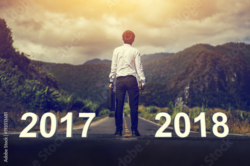 2017 , 2018 years and Happy new year concept ,Businessman walk though between 2017 and 2018 years