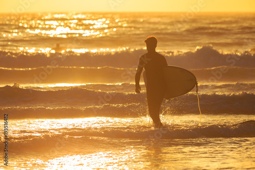 A surfer heading out