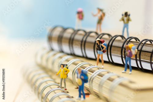 Miniature people: travelers standing on the book, traveling to destination. Image use for travel business concept.