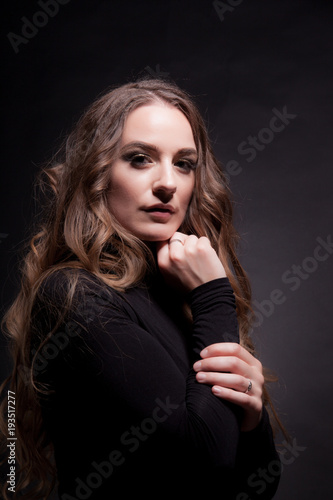 Portrait of a beautiful girl with long hair on a dark background in the studio