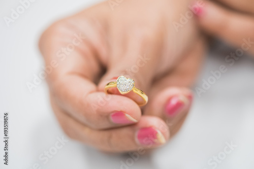 Gold ring with diamond heart in woman hand
