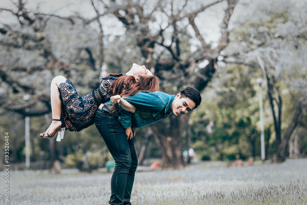 Obraz premium Asian couple lovers under a vast field of nature in a park.