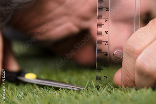 Man Using Measuring Scale While Cutting Grass photo