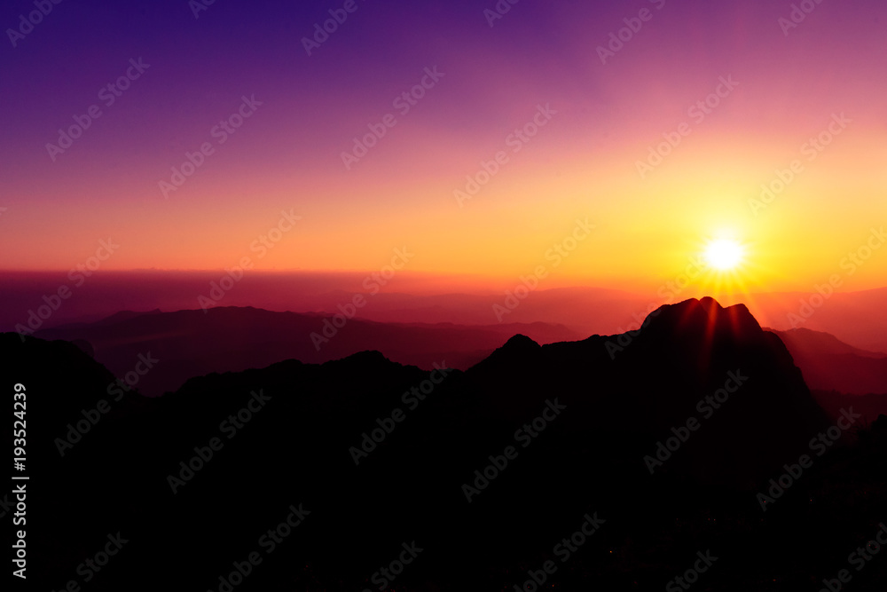 A stunning sunset or sunrise scene of silhouette mountain peaks and purple ridges with the twilight background, the purple sky and the pink-yellow skyline, captured at chiangmai, thailand