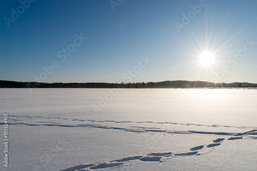 Footprints and tracks on snow at frozen lake