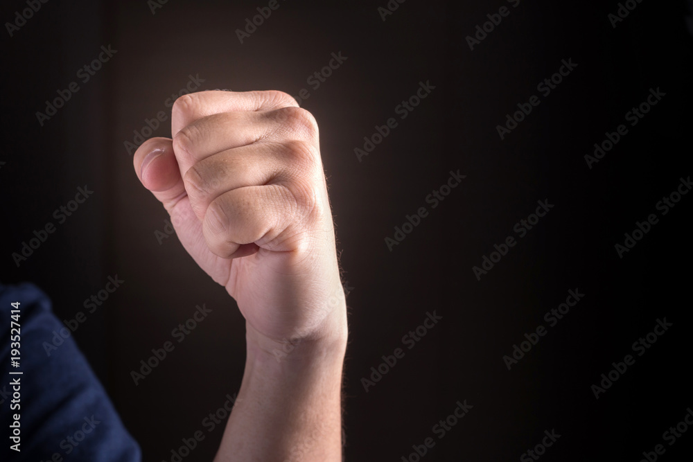 hand with clenched a fist on a black background