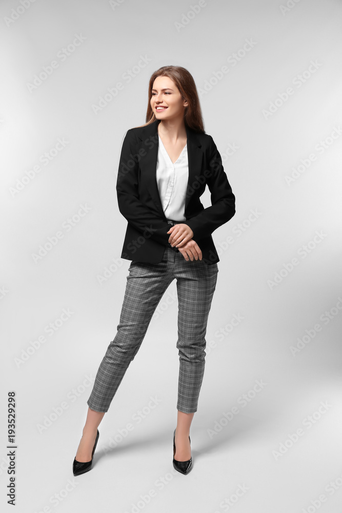 Beautiful young woman in elegant suit on light background Beautiful young woman in elegant suit on light background
