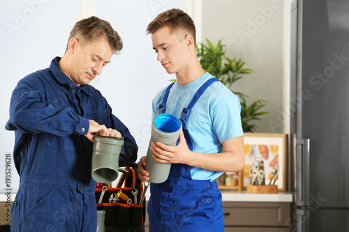 Fotografie Plumber with young trainee on kitchen