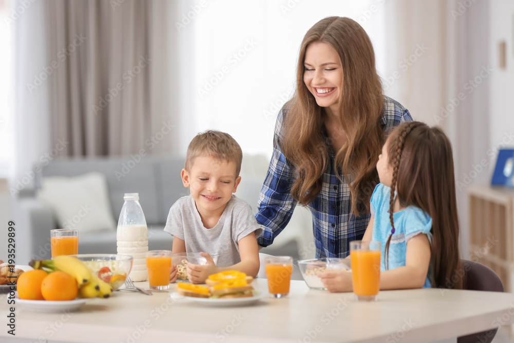 Mother with children having breakfast in kitchen