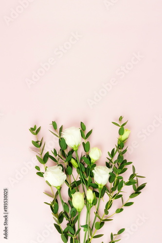 bouquet of white flowers and twigs of eucalyptus on a pale pink background. top view. copy space