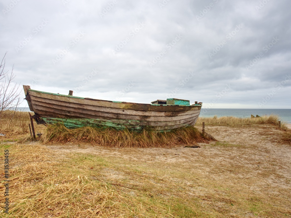 Abandoned fishing boat on bank of sea. Morning silent bay within windless.
