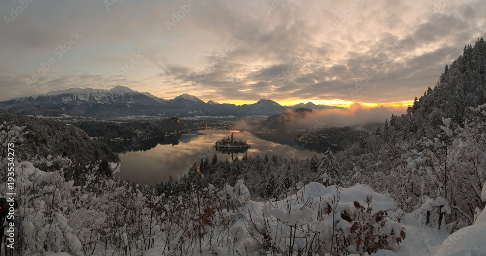 Winter sunrise at Bled lake with snow on the trees
