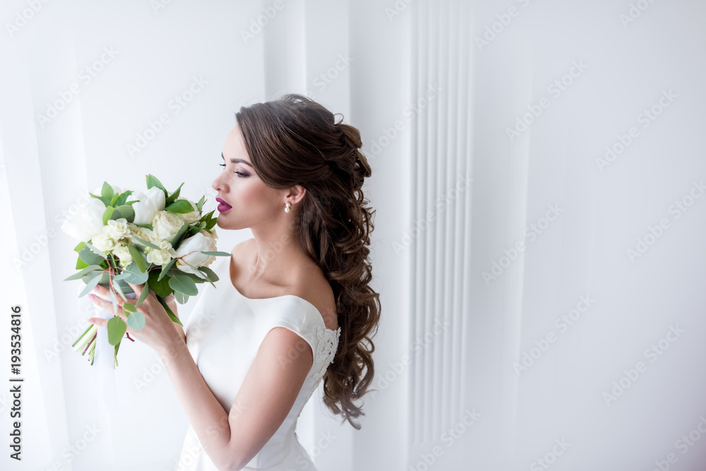 attractive bride in white dress sniffing wedding bouquet attractive bride in white dress sniffing wedding bouquet