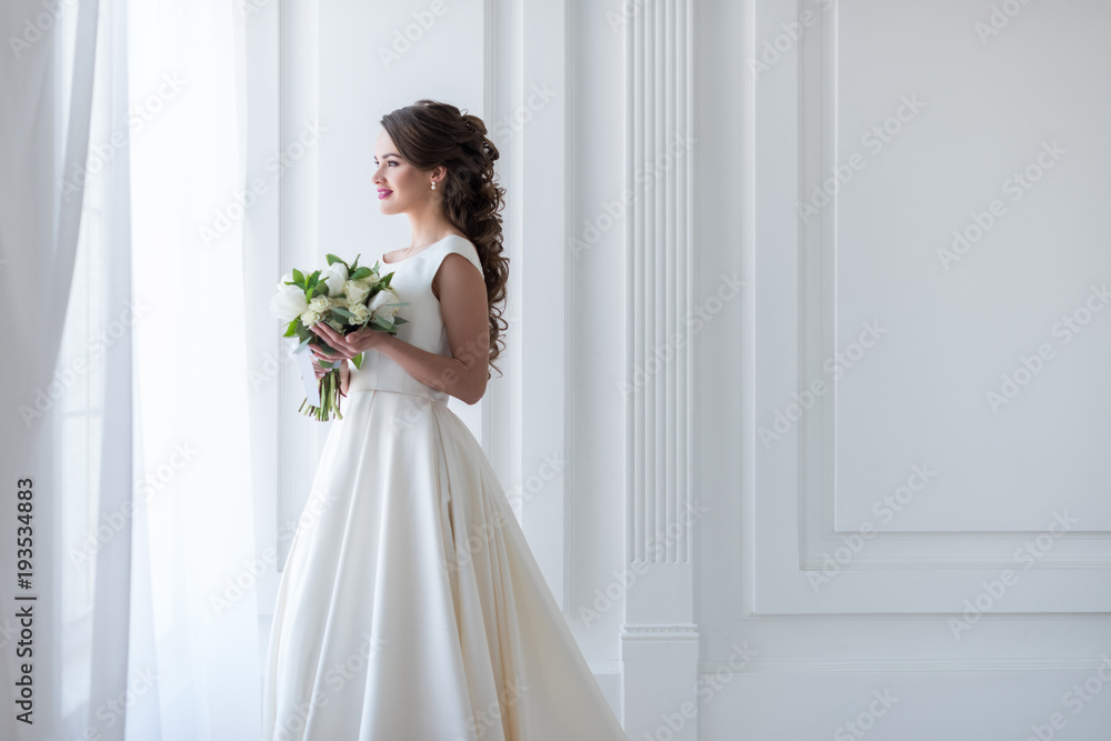 attractive happy bride posing in traditional dress with wedding bouquet attractive happy bride posing in traditional dress with wedding bouquet