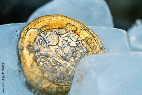 Frozen New British one pound sterling coin up close macro inside ice cubes photo