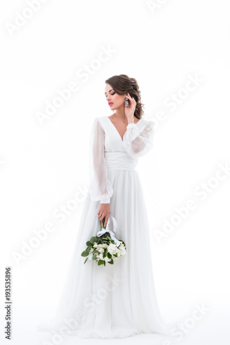 tender bride posing in elegant dress with wedding bouquet, isolated on white