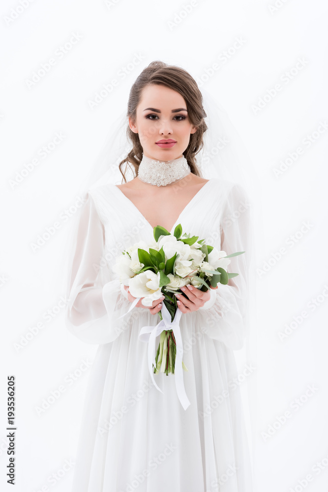 attractive bride in traditional dress and veil holding wedding bouquet, isolated on white