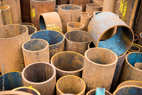 Rusty metal pipe sections of different diameter stored in a warehouse