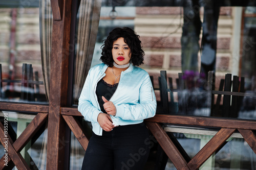 Stylish african american plus size model against wooden cafe at winter day. © AS Photo Family