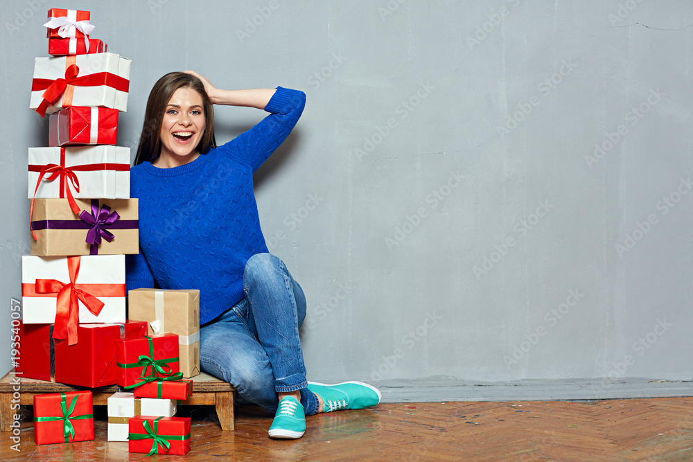 Happy woman sitting on floor with heap of gift boxes. Happy woman sitting on floor with heap of gift boxes.
