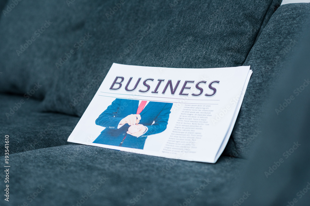 close up view of business newspaper on grey sofa close up view of business newspaper on grey sofa