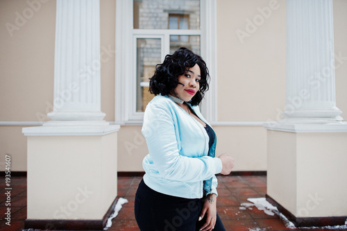 Stylish african american plus size model at streets of city on winter day.