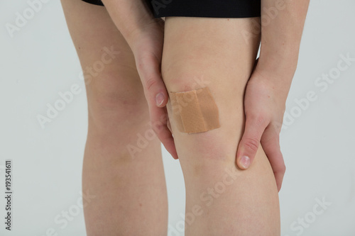Pflaster auf dem Knie einer schönen jugnen Frau