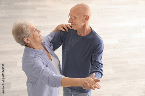 Cute elderly couple dancing in empty room