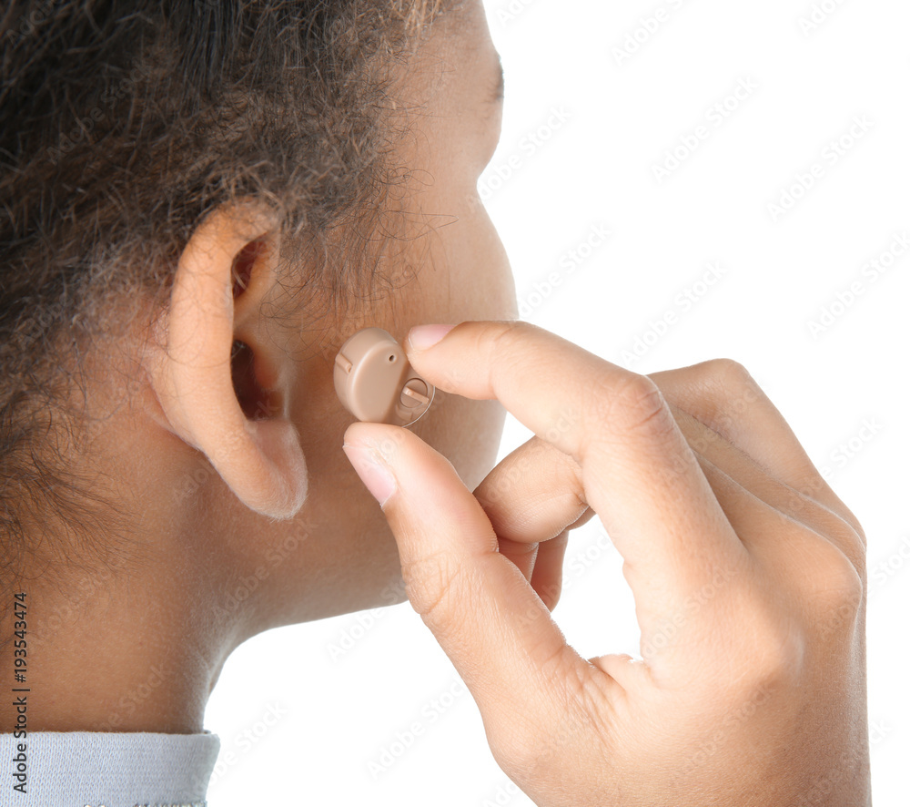 Fototapeta premium Little girl putting hearing aid in ear, closeup
