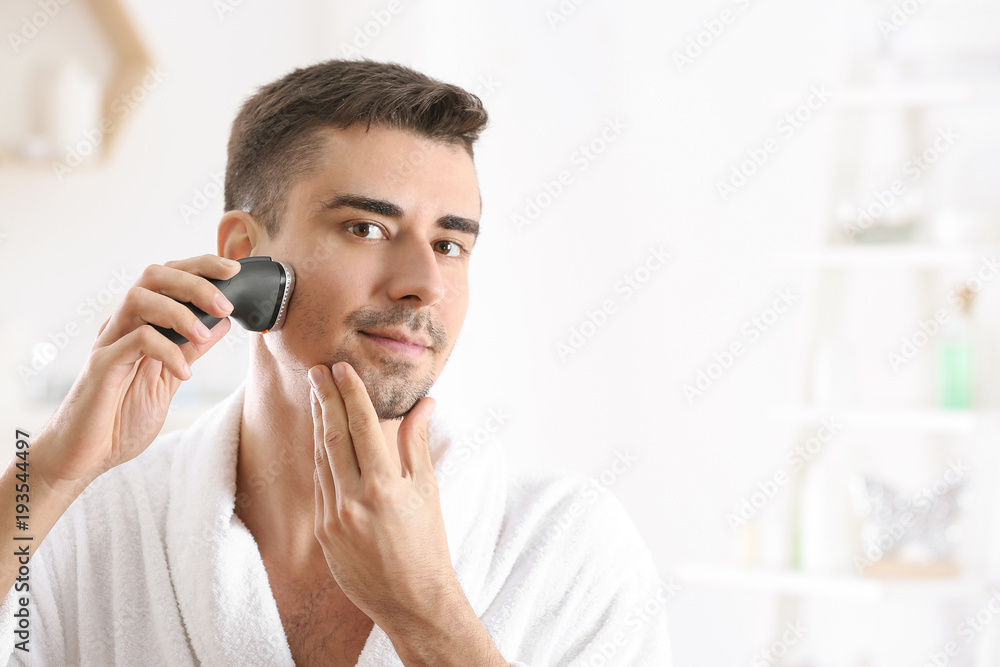 Handsome young man shaving in bathroom Handsome young man shaving in bathroom