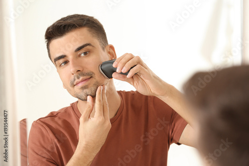 Handsome young man shaving in bathroom