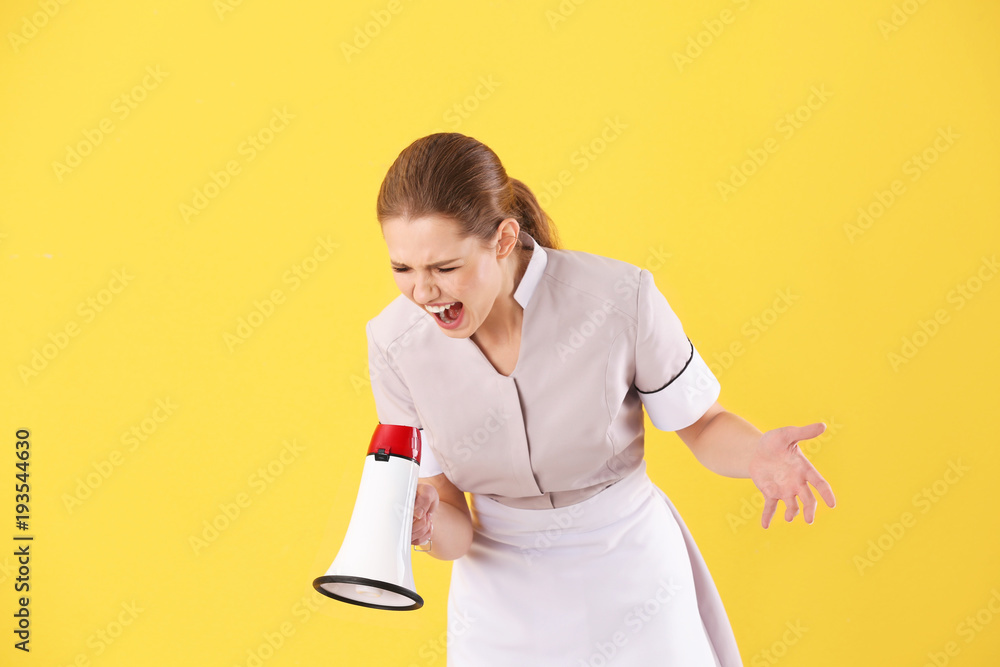 Young chambermaid shouting into megaphone on color background Young chambermaid shouting into megaphone on color background