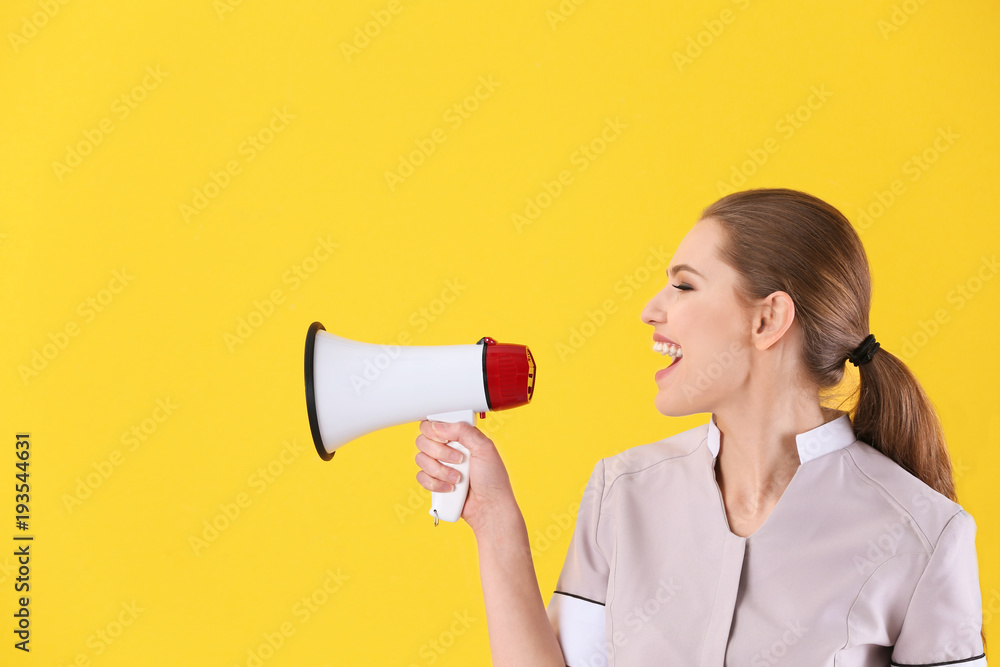Young chambermaid with megaphone on color background Young chambermaid with megaphone on color background