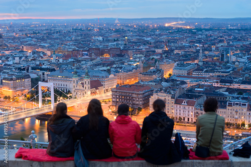 Group of sitting people overlooks Budapest city from top viewing point on Gellert hill photo