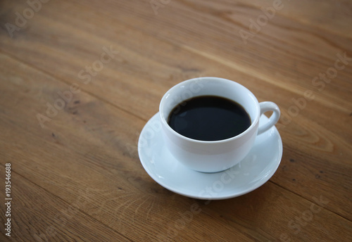 Black coffee in white cup on wood