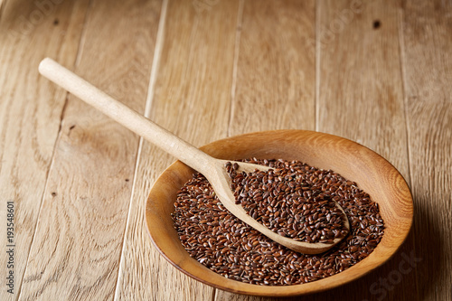 Wooden spoon with flax seeds in a plate on rustic background, top view, close-up, shallow depth of field