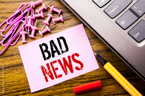 Handwritten text showing Bad News. Business concept for Failure Media Newspaper written on pink sticky note paper on the wooden background next to keyboard. With red pen. photo