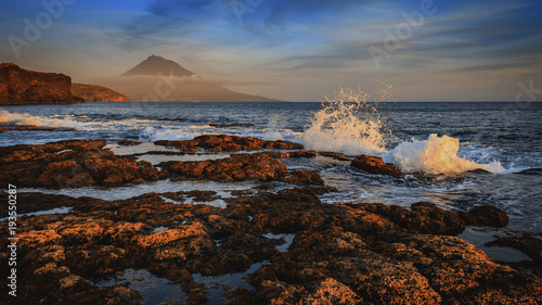 Sonnenuntergang an der Küste von Faial auf den Azoren, mit Blick auf den Vulkan Pico, dem höchsten Gipfel Portugals