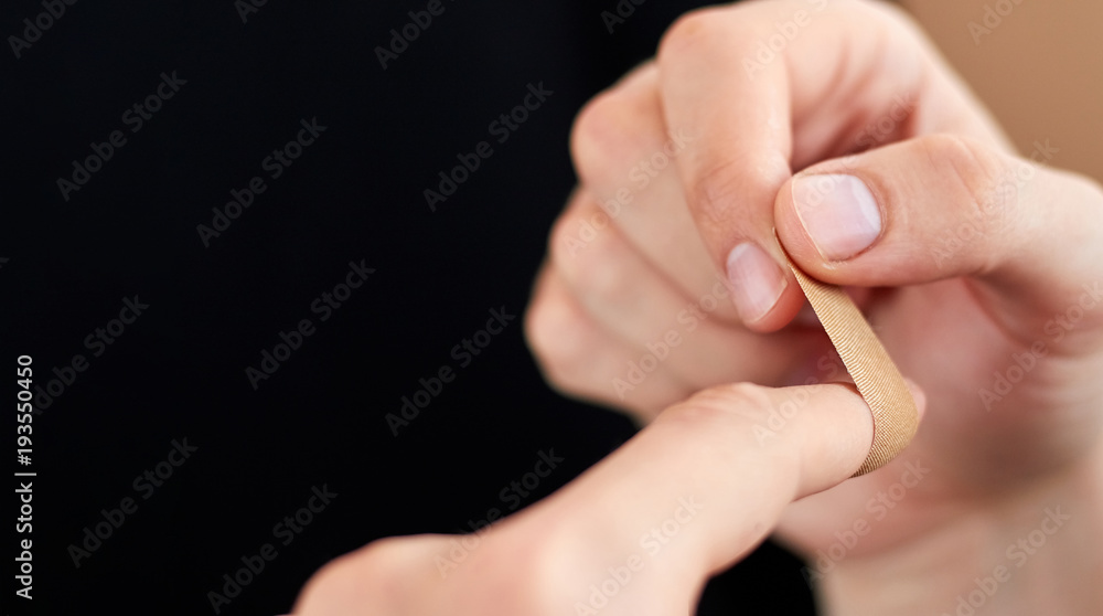 Close up bandage on an injured finger isolated on black with copyspace Close up bandage on an injured finger isolated on black with copyspace